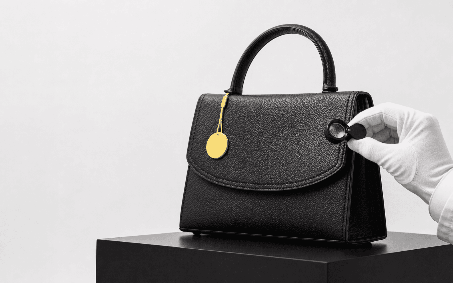 An authenticator examining the stitching of a black leather handbag